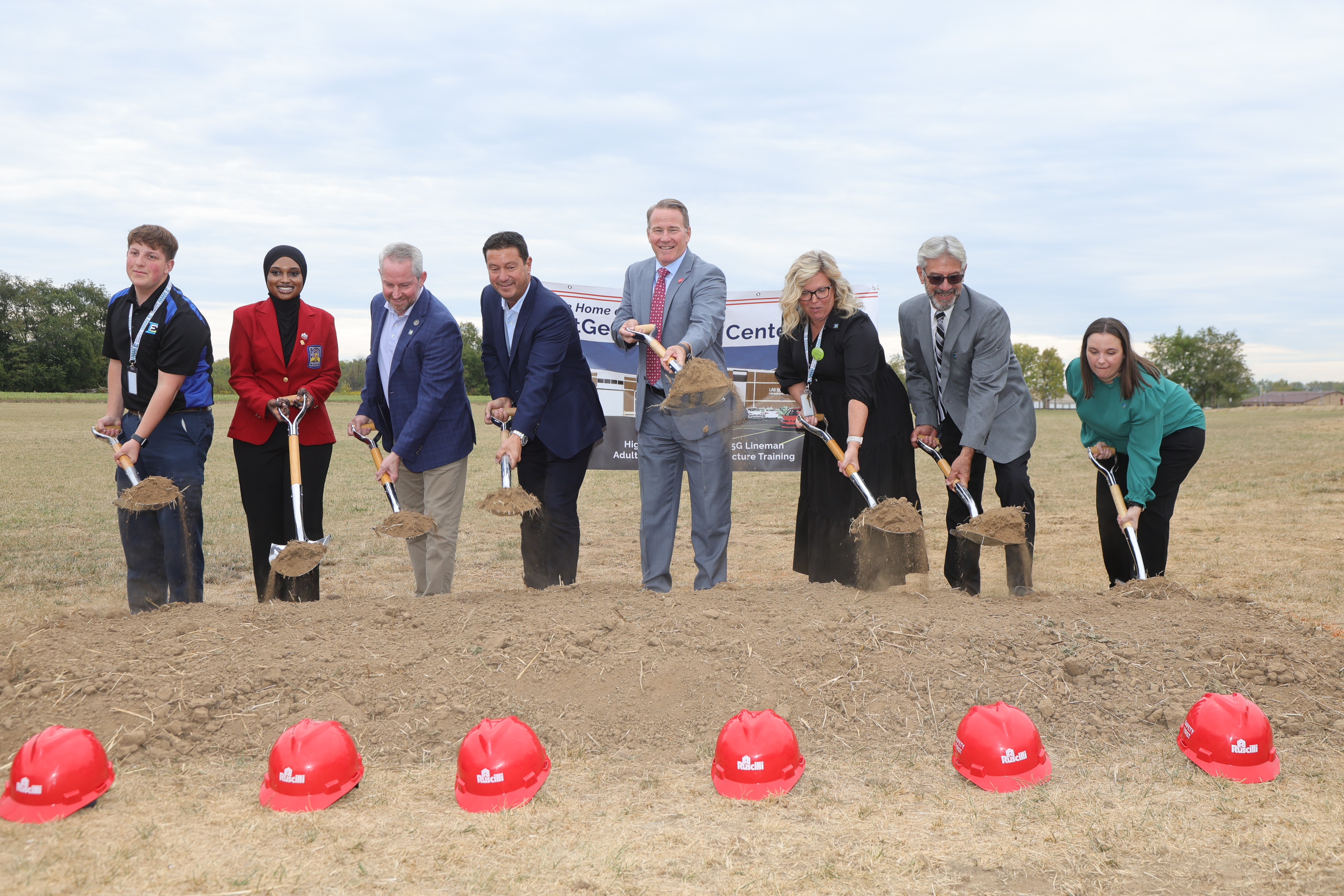 A group of individuals with shovels in hand dig up the first piles of dirt commemorating the beginning of construction on theNextGen Training Center