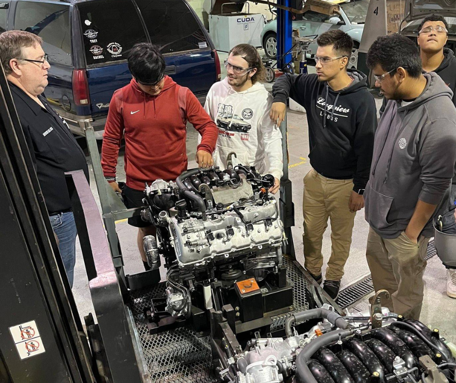 Lobo automotive instructor and students talk about engines that just arrived.