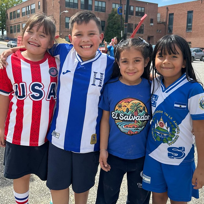 cuatro niños posan vistiendo camisetas de Honduras, el Salvador y Estados Unidos en Clay Hill por el mes de la Herencia Hispana