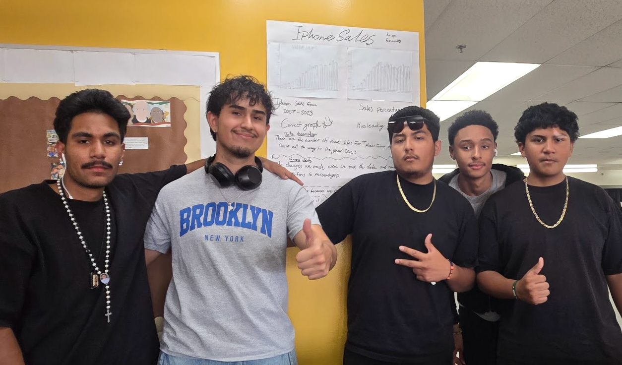 5 students smiling and holding up peace signs