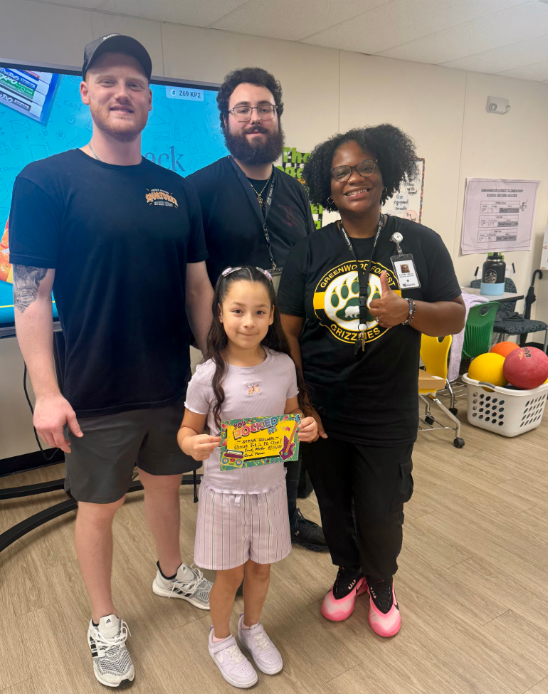 Student of the Week in Pink shirts and shorts with 3 PE Teachers 
