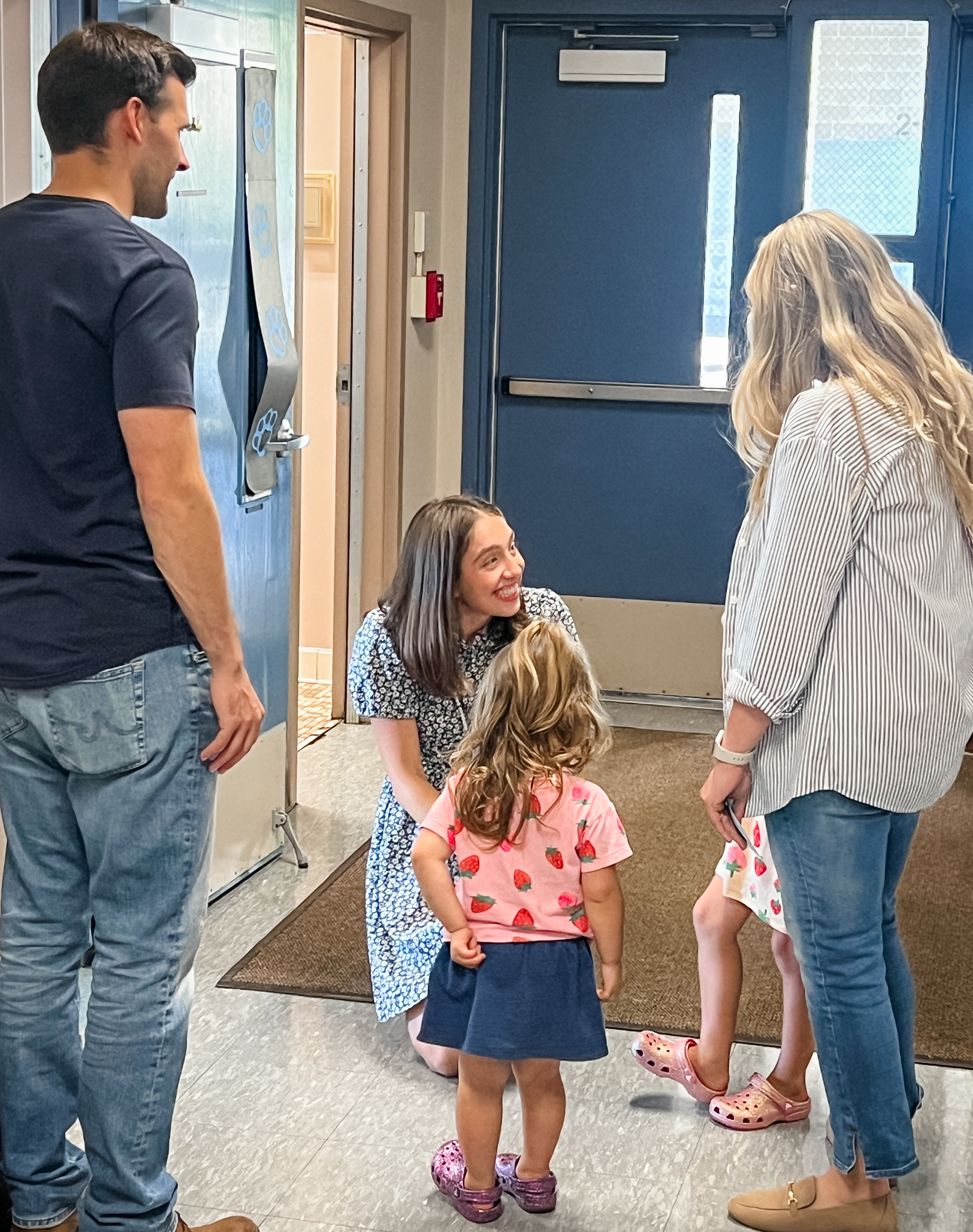 Westwood Teacher kneeling down and greeting student and their family at open house