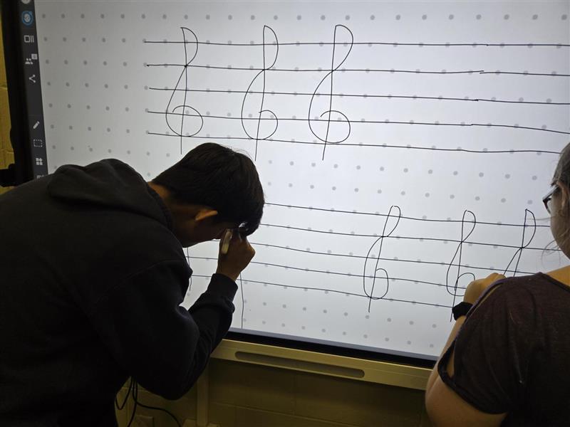 Damian and Paige practicing drawing the treble clef