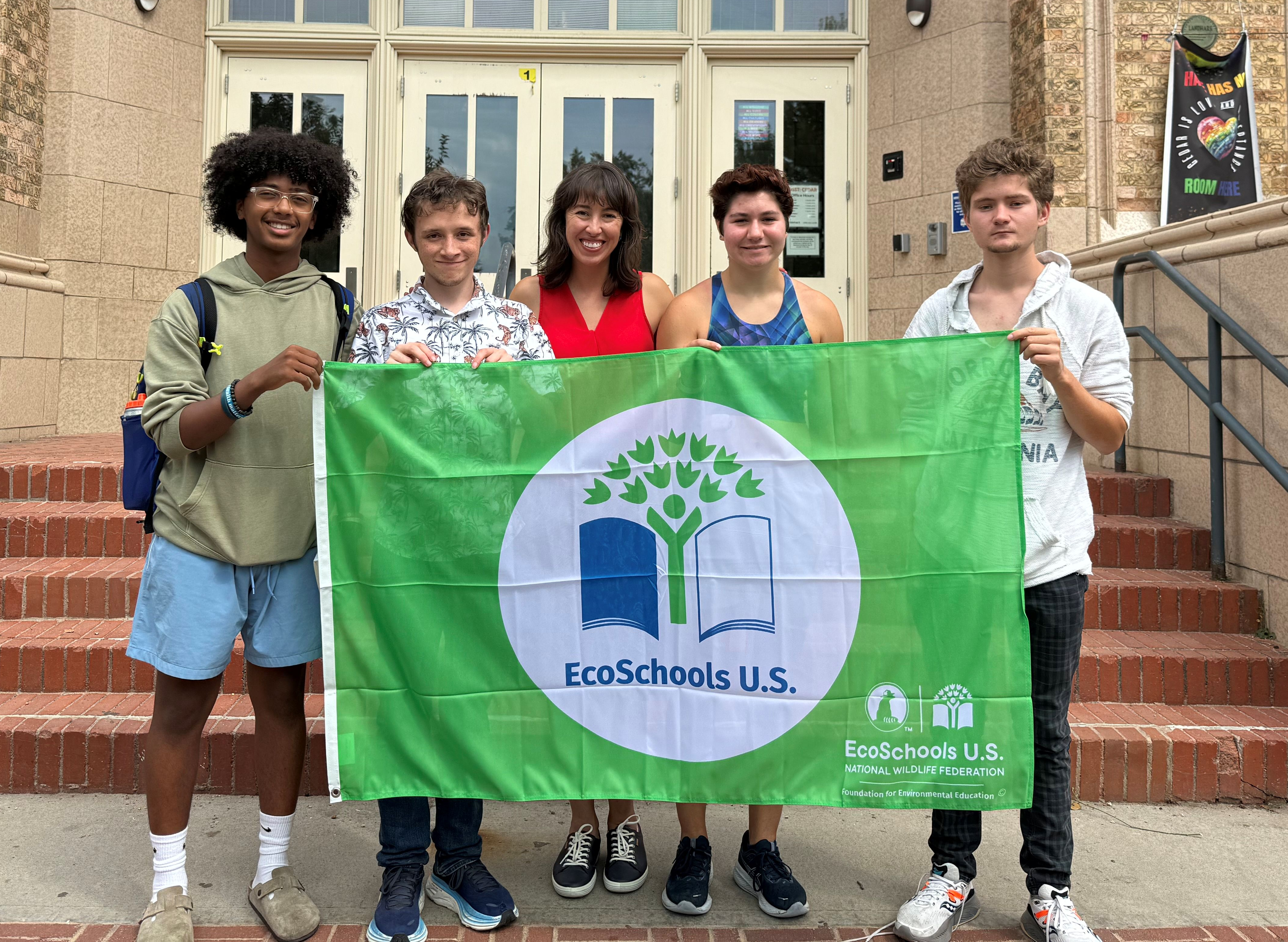 students and staff displaying their EcoSchools Green Flag outside of DSST Cedar