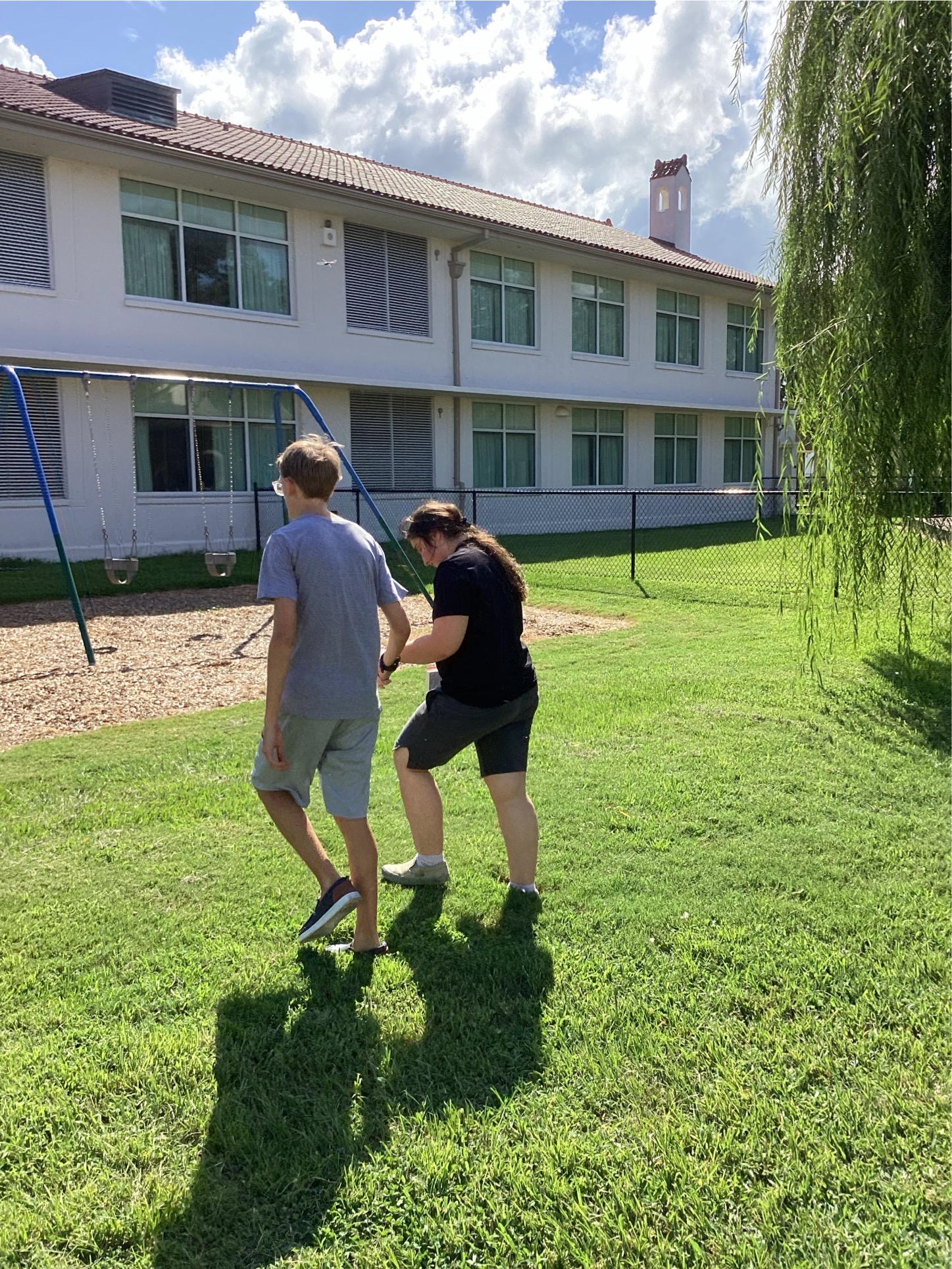 2 students walking together through the grass to toward the swings