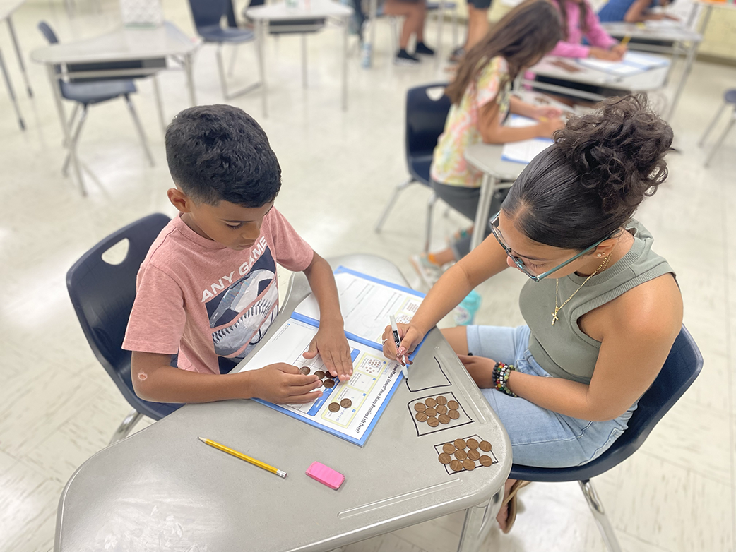 Student working with teacher on math facts using pennies