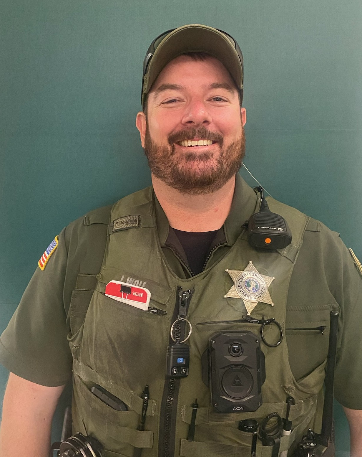 a man in front of a green background wearing sheriff's uniform