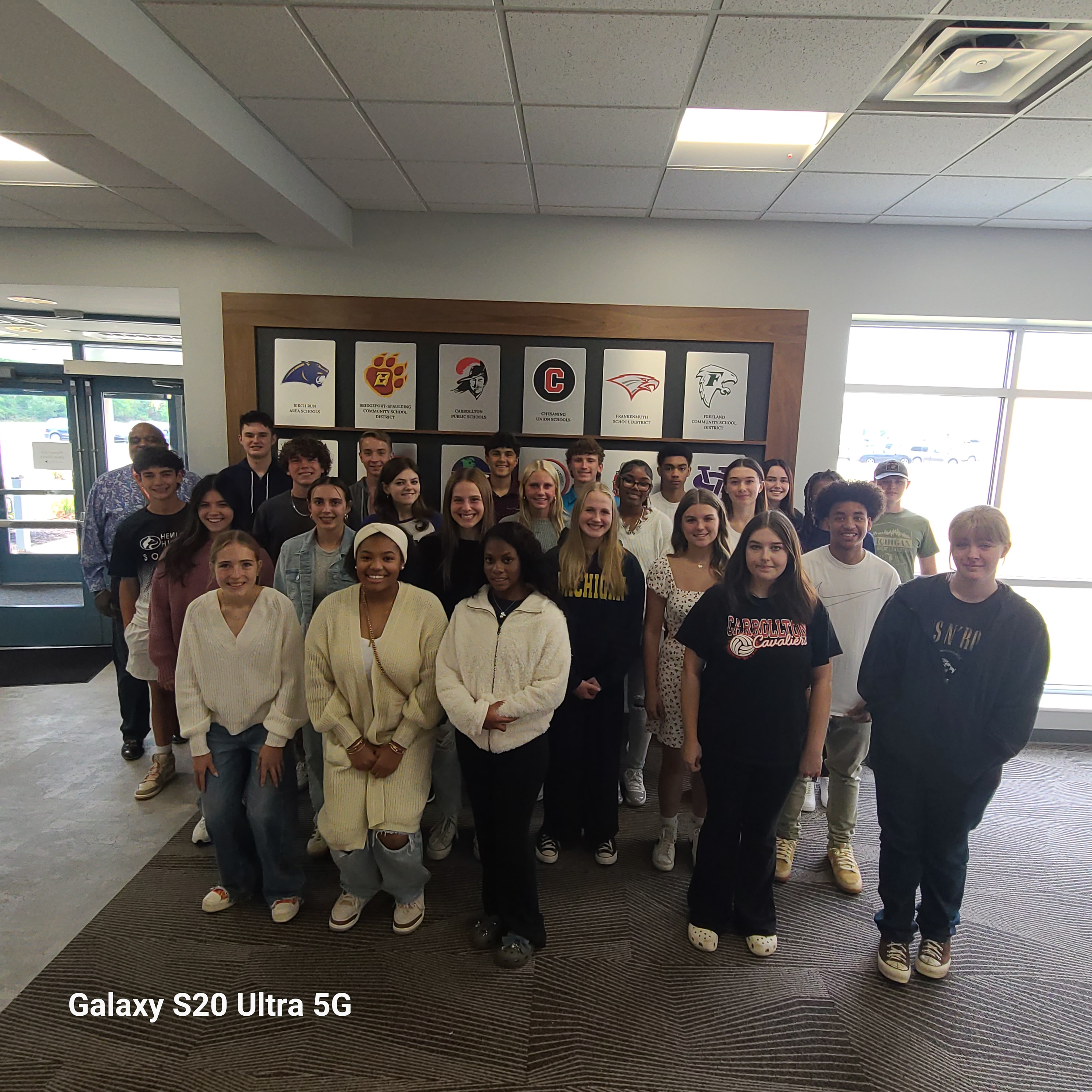 student ambassadors in front of a sign of the school district logos at the ISD