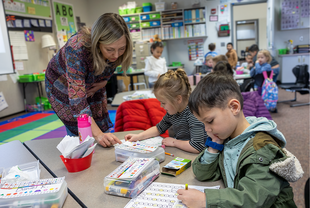 A teacher works with two primary school students