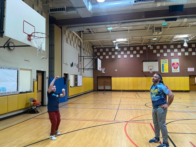 Student and staff member playing basketball
