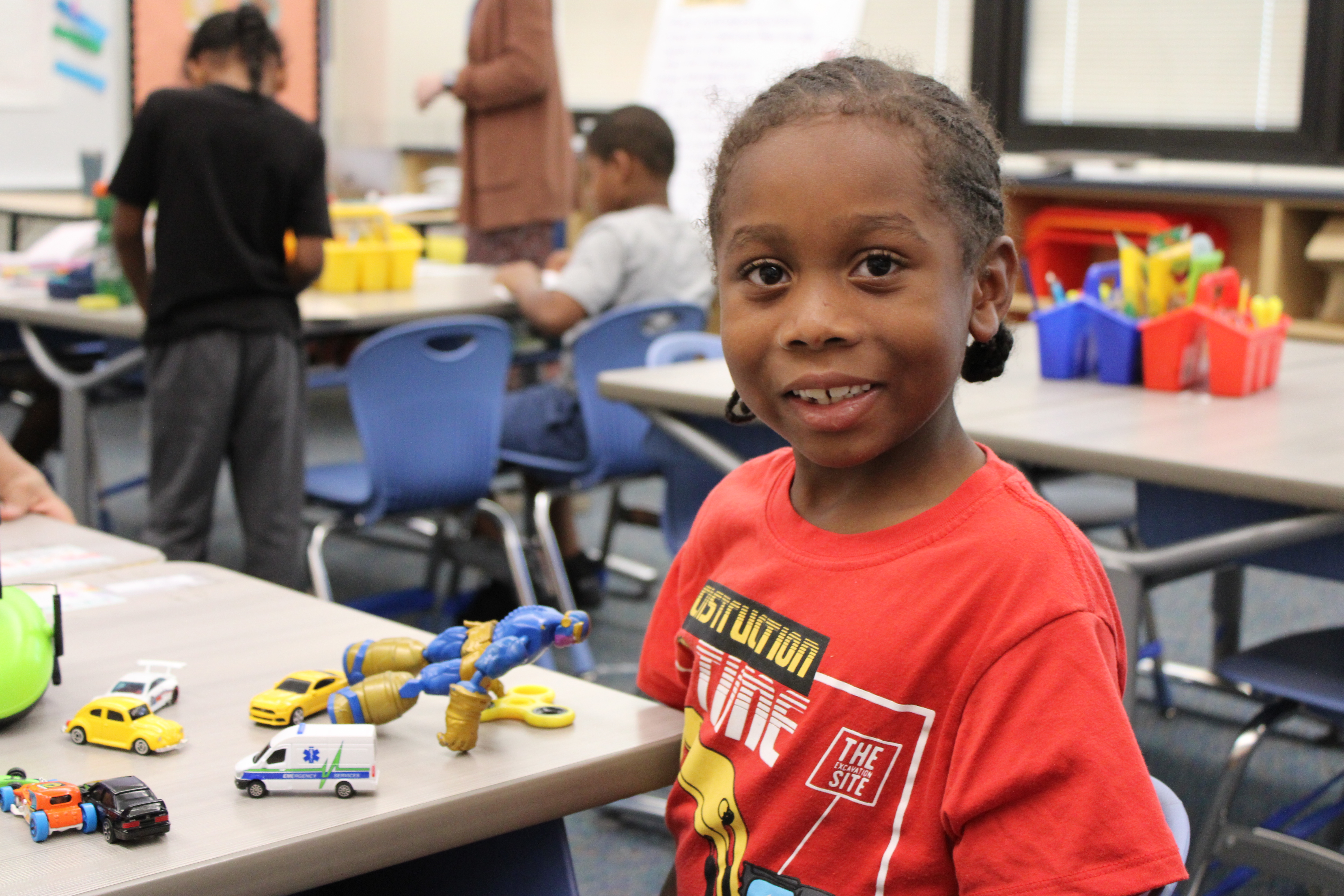 student smiling at his desk with toys