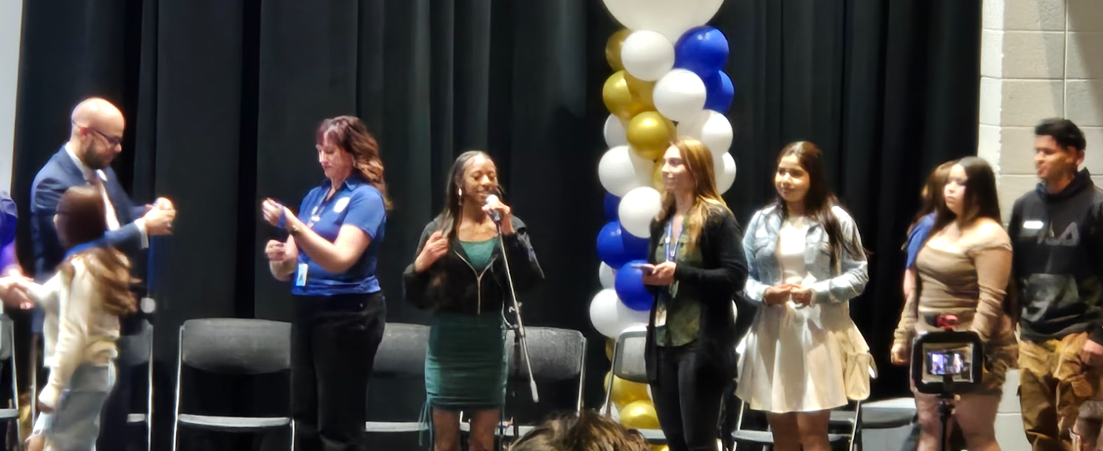 Students stand onstage with balloons