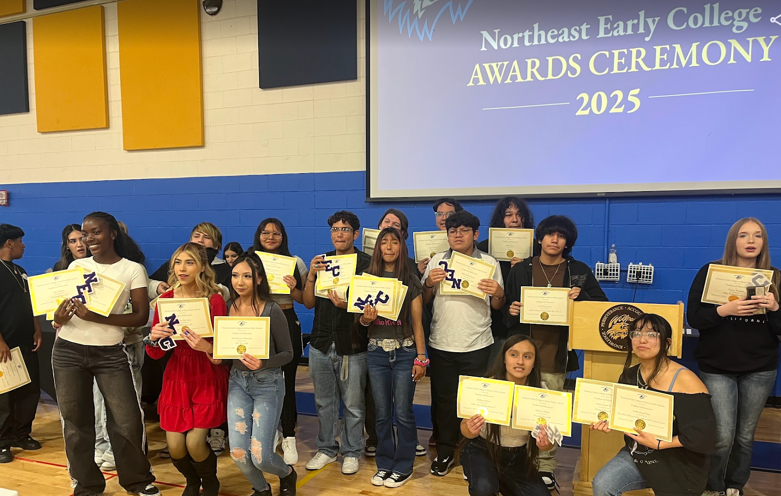 students holding certificates under a sign that says "Northeast Early College Awards Ceremony"