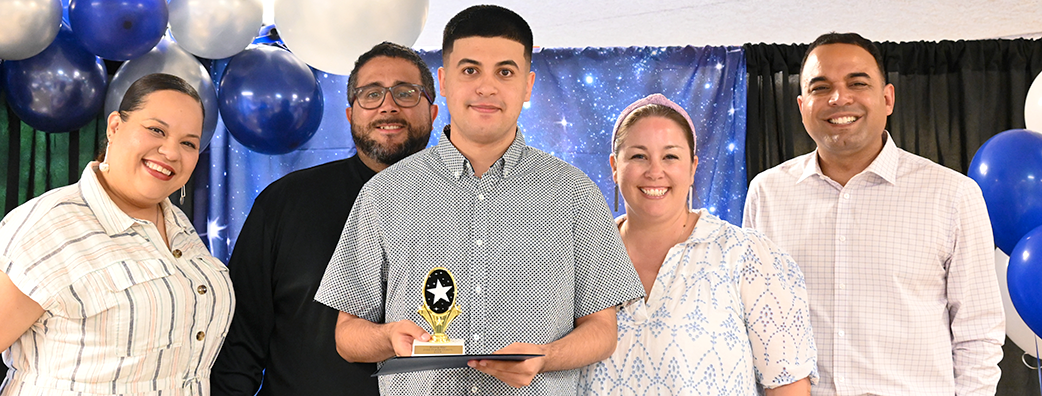 Student holding Rising Star award, standing in front of four adults 