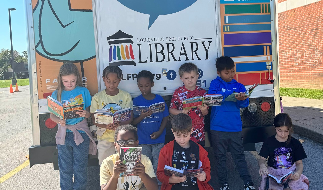 Students reading in front of library truck.