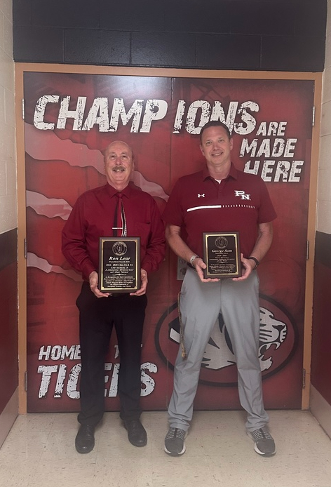 two men standing in front of doors holding plaques