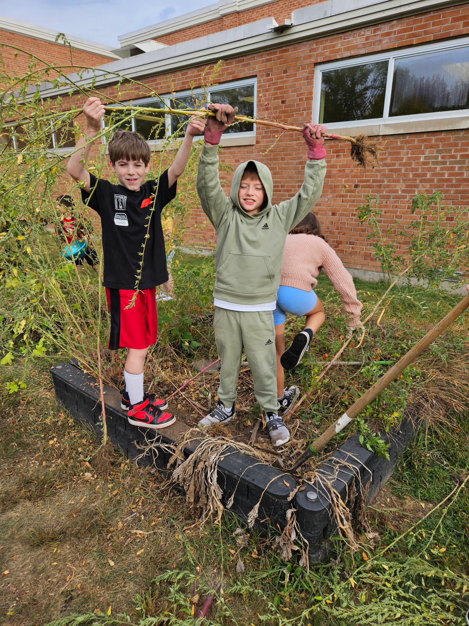 4th grade in the garden and holding up sticks and roots that were dug up