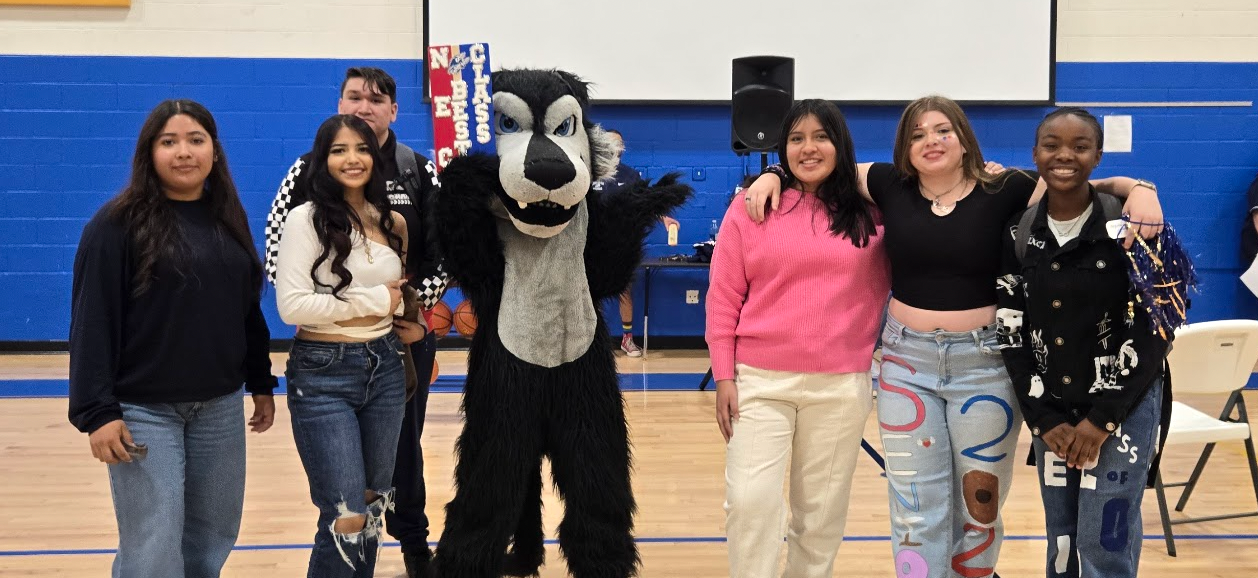 5 students smiling at the camera with the wolf mascot in the gym