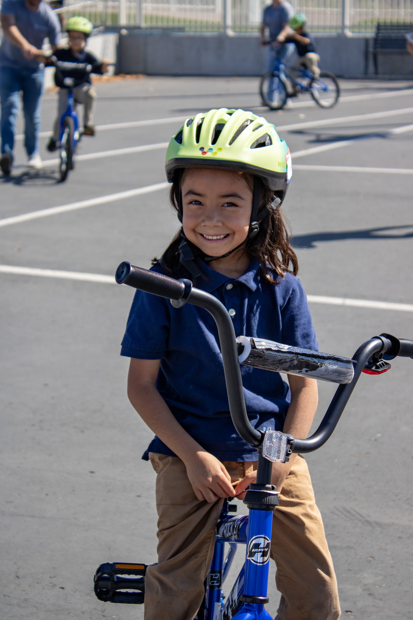 A student smiles while riding her bike on the blacktop.
