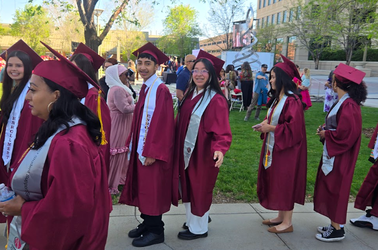 CCA graduates walking on the lawn in their caps and gowns