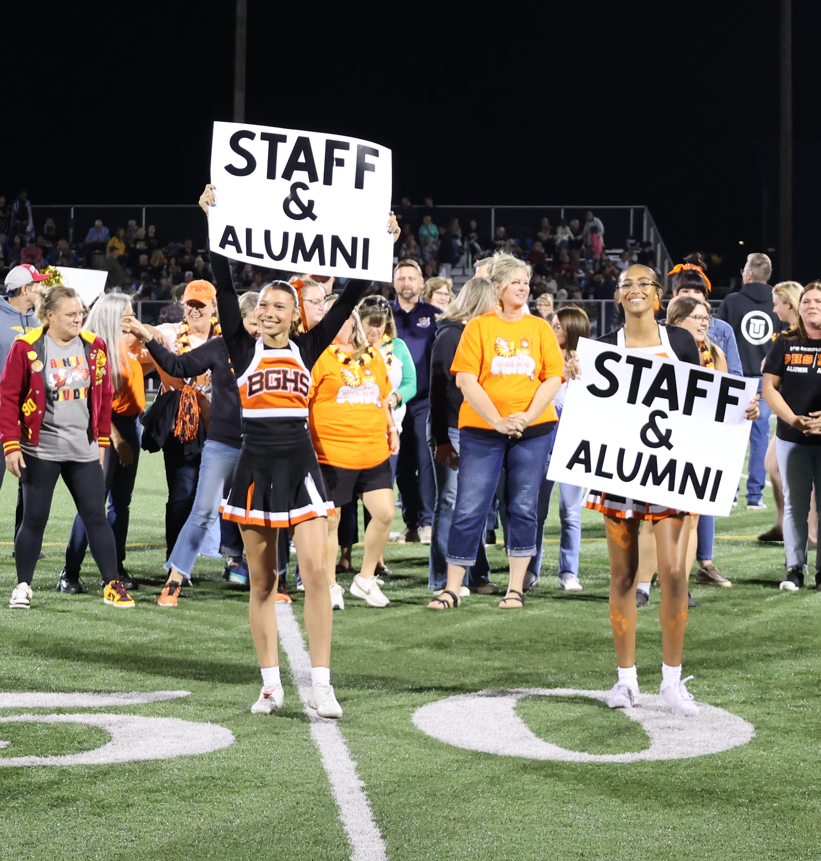 Cheerleaders hold up signs that say "Staff and alumni" to recognize those who have contributed to Battle Ground's legacy