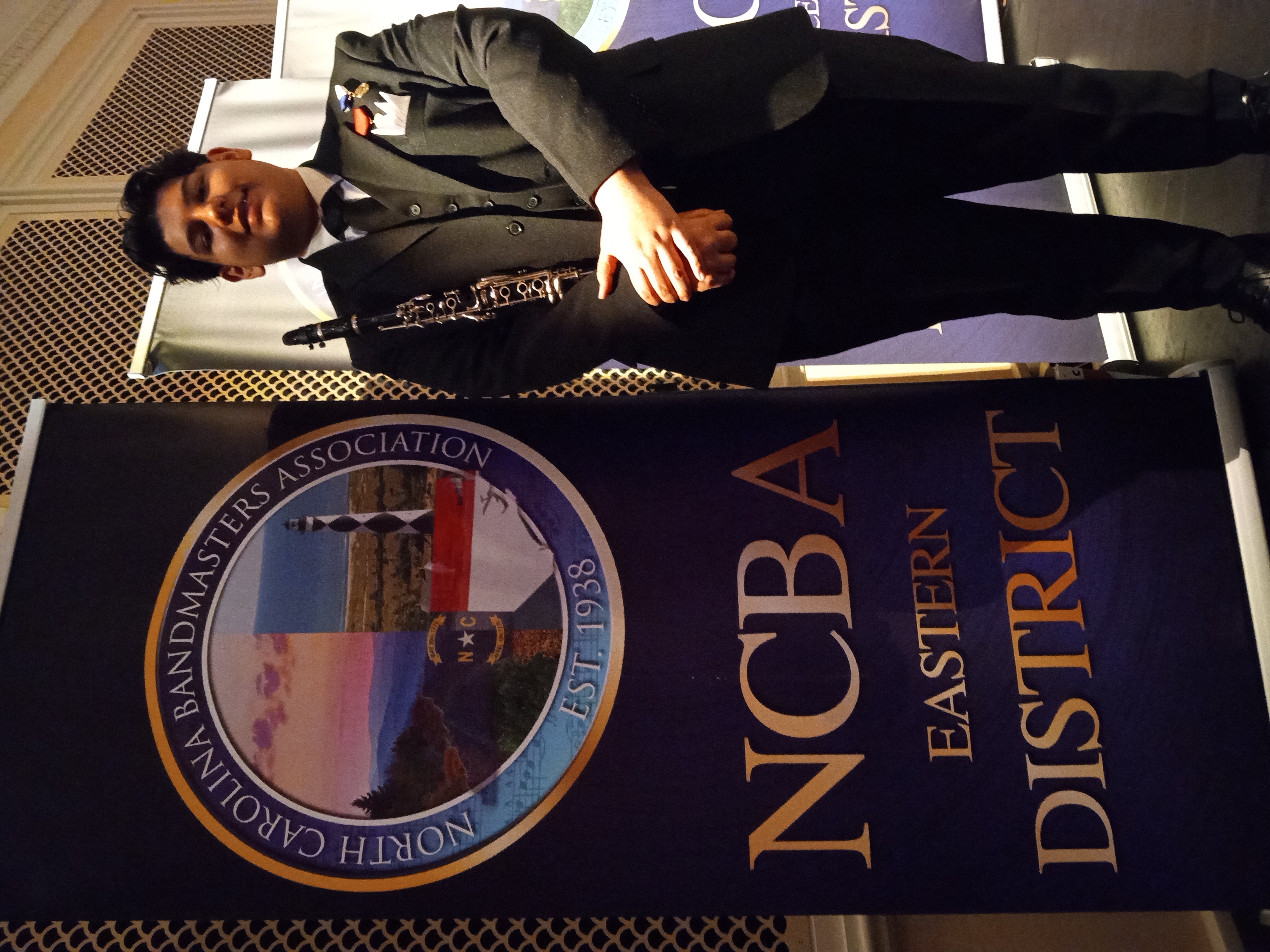 young man standing beside a sign that raeads NCBA Eastern District