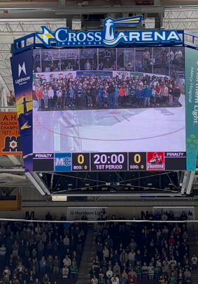 Students standing together on the ice singing the NationalAnthem