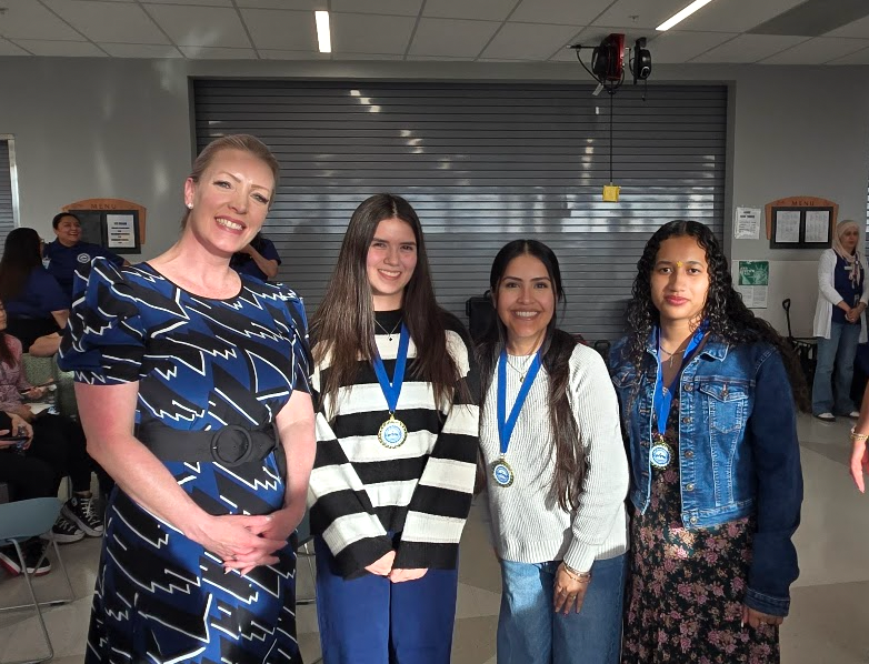 3 students wearing medals stand next to the principal