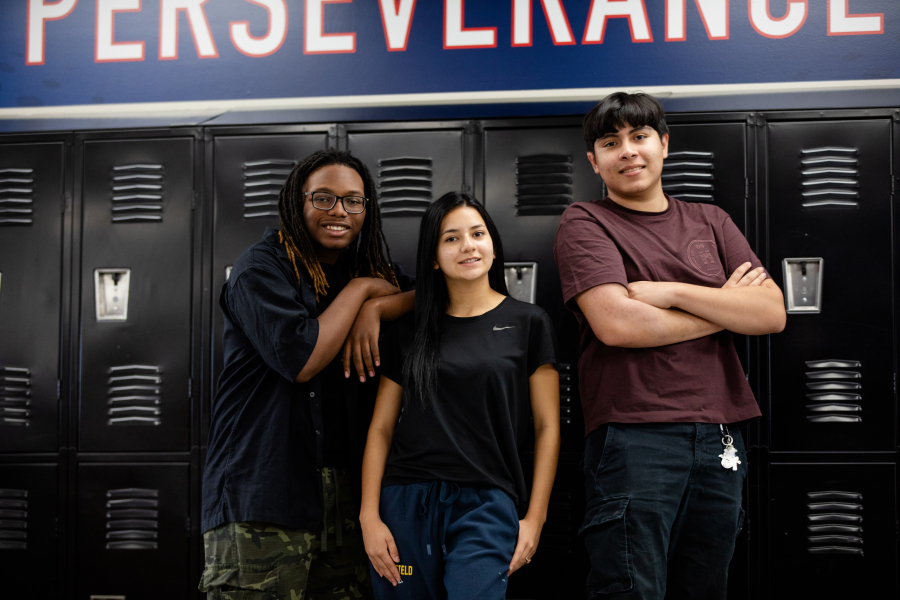 NEC students standing in front of lockers crossing their arms and smiling.
