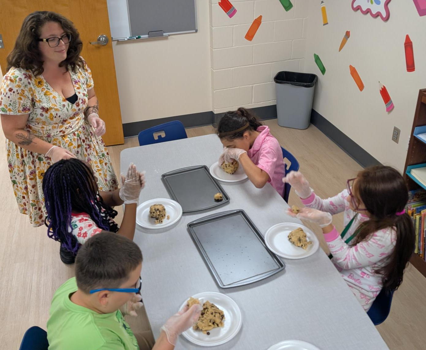 Mrs. Heather assisting students making and baking cookies.