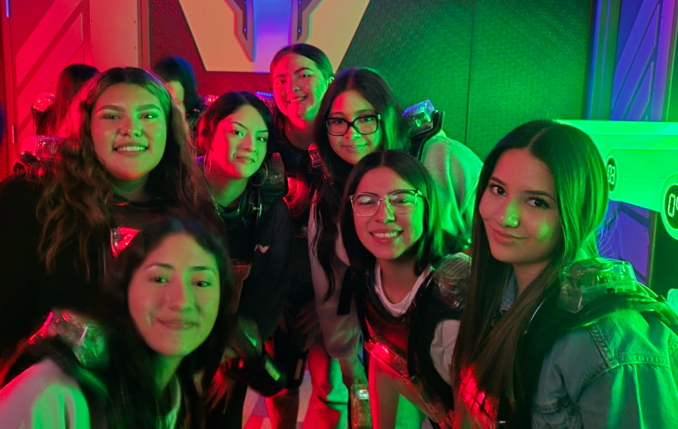 Selfie of 7 students smiling in green/red lighting