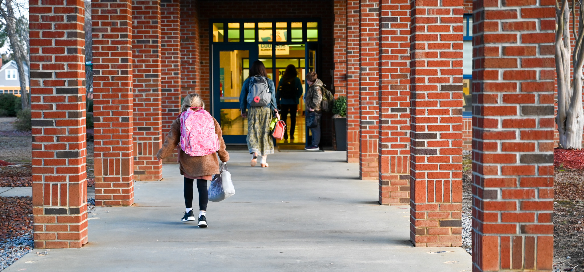 outside of school building with students walking inside