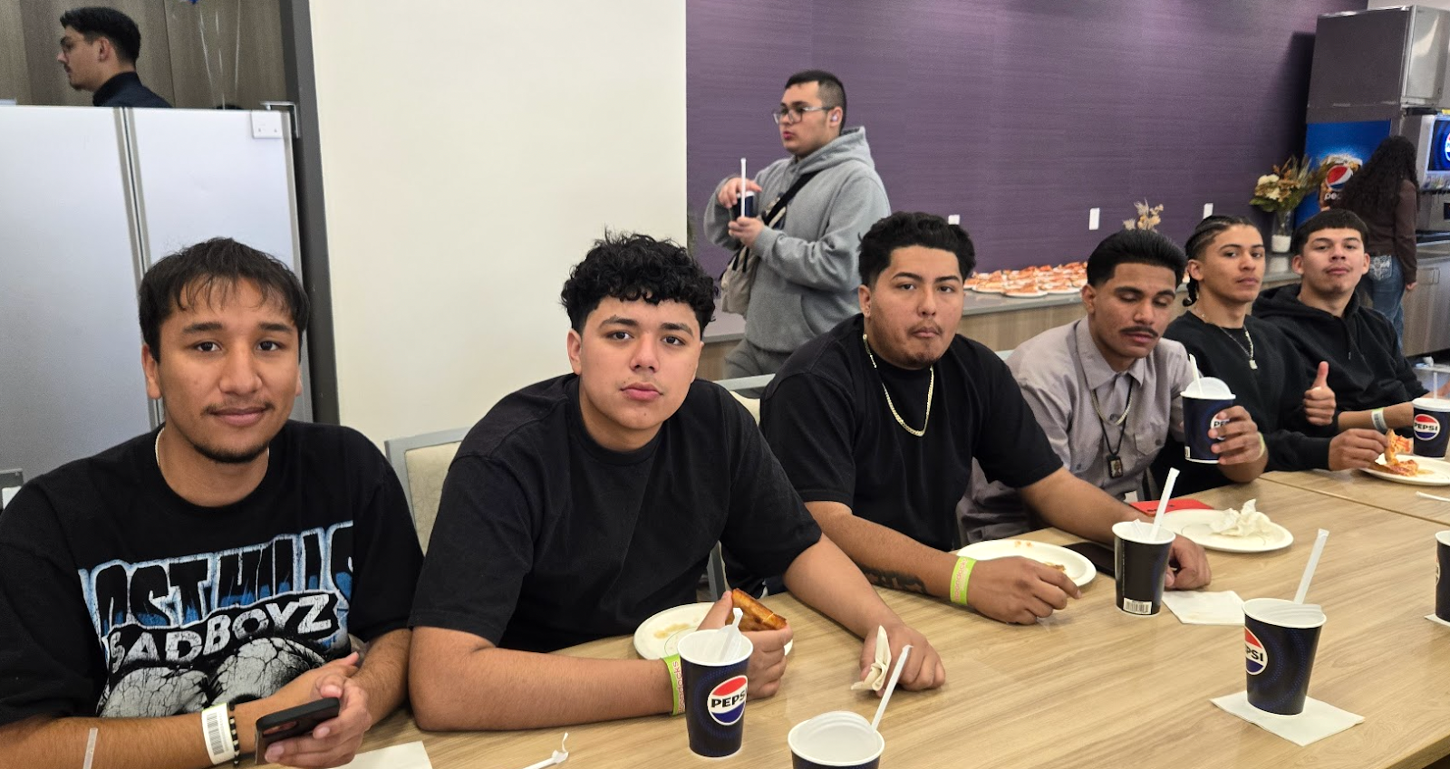 6 students sitting at a table with food and drinks, smiling at the camera